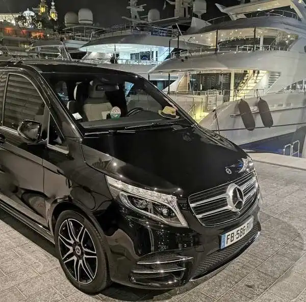 Extra long van parked in front of a yacht in Cannes harbor